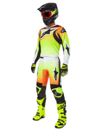 Motocross rider wearing the Alpinestars 2025 Fluid Wurx Pants in Yellow and Black, featuring a vibrant yellow-to-white gradient with orange and black accents, shown as part of a complete racing gear set with a matching jersey, black helmet, and neon yellow boots.