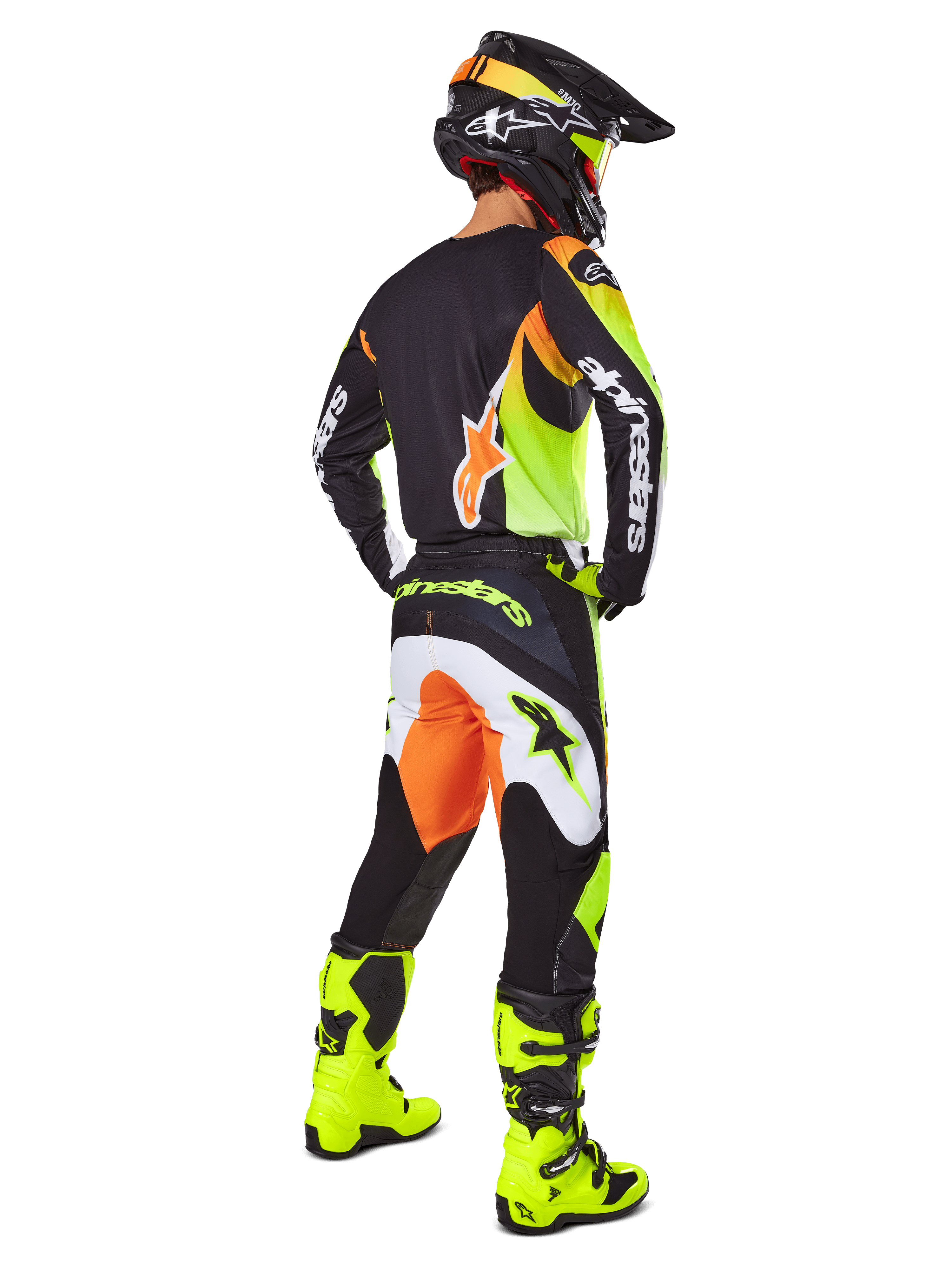 Motocross rider from a rear view wearing the Alpinestars 2025 Fluid Wurx Gear Set, black jersey with yellow and orange accents, matching black pants with white and orange panels, bright yellow boots, and a black helmet, complete off-road racing outfit