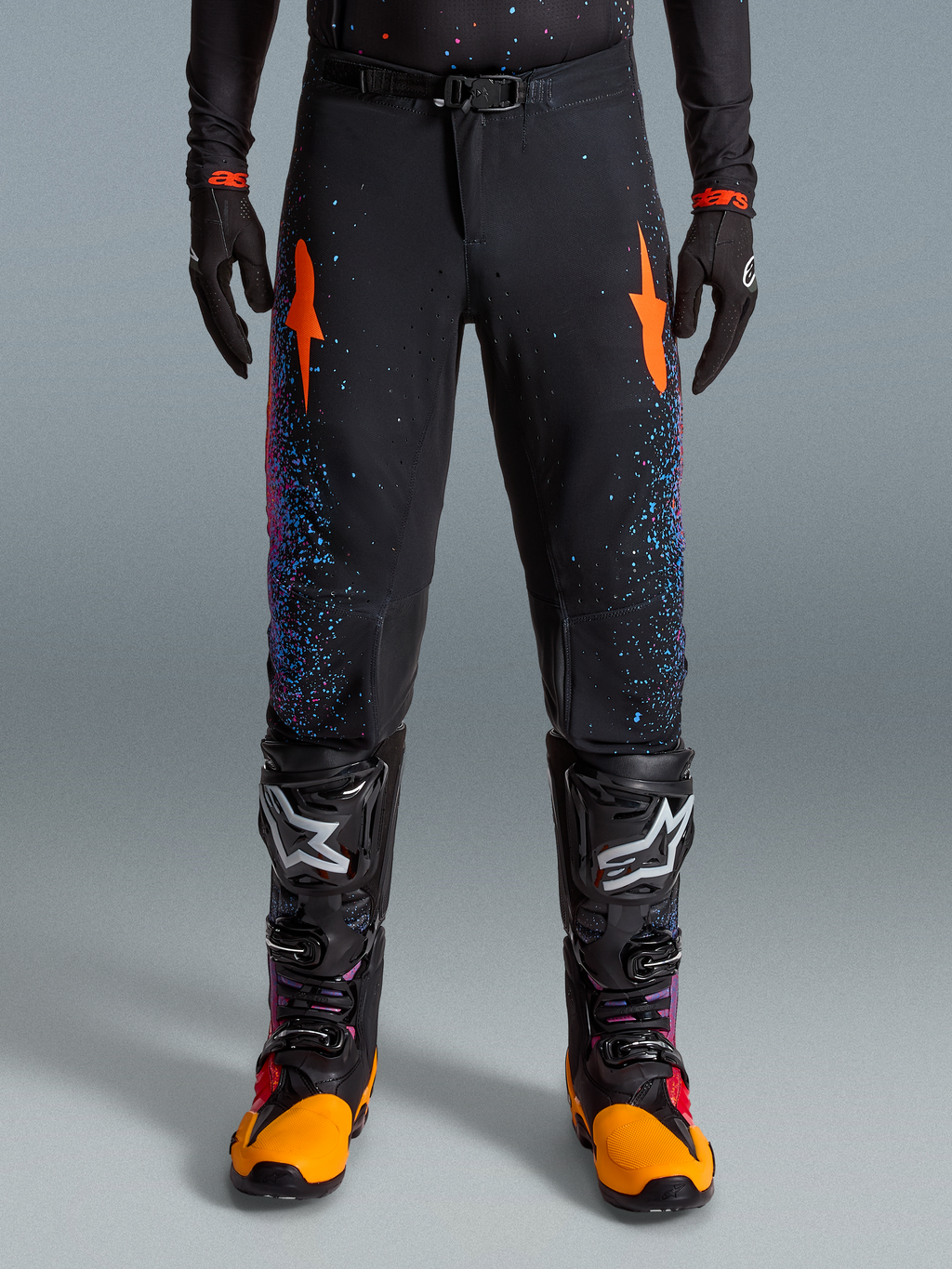 Limited Edition Supertech Black Hole Pants, Motocross Racing Pants, Black with Blue and Pink Speckles, Orange Star Designs, Premium Motorsports Gear, Worn with Black Racing Gloves and Boots