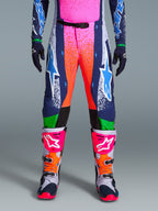 Alpinestars Limited Edition Supertech Records Pants, Motocross Pants, Multicolor featuring vibrant pink and orange splash graphics, navy panels with blue star logos, and green accents. Worn with matching jersey and grey, pink, and orange motocross boots.