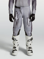 Alpinestars Youth Fluid Amber Pants, durable grey and black motocross pants for young riders in an off-road setting.