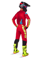Motocross rider seen from the back wearing the Alpinestars 2025 Supertech Maker Jersey, Bright Red and Yellow Fluo, matching pants with yellow branding, yellow fluo boots, and a black and red helmet, coordinated outfit for pro-level off-road racing