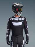 Alpinestars 2026 Racer Air Riway Jersey, Black and White motocross jersey with 'astars' branding, worn by a rider with matching black helmet, goggles, and pants, featuring breathable mesh panels for off-road racing.