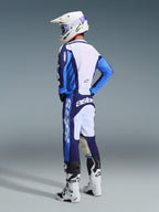 Motocross rider wearing the 2026 Racer Riway Jersey in Ucla Blue and White, paired with matching blue and white motocross pants, a white helmet, and white boots, shown from a back three-quarter view for a complete off-road racing look.
