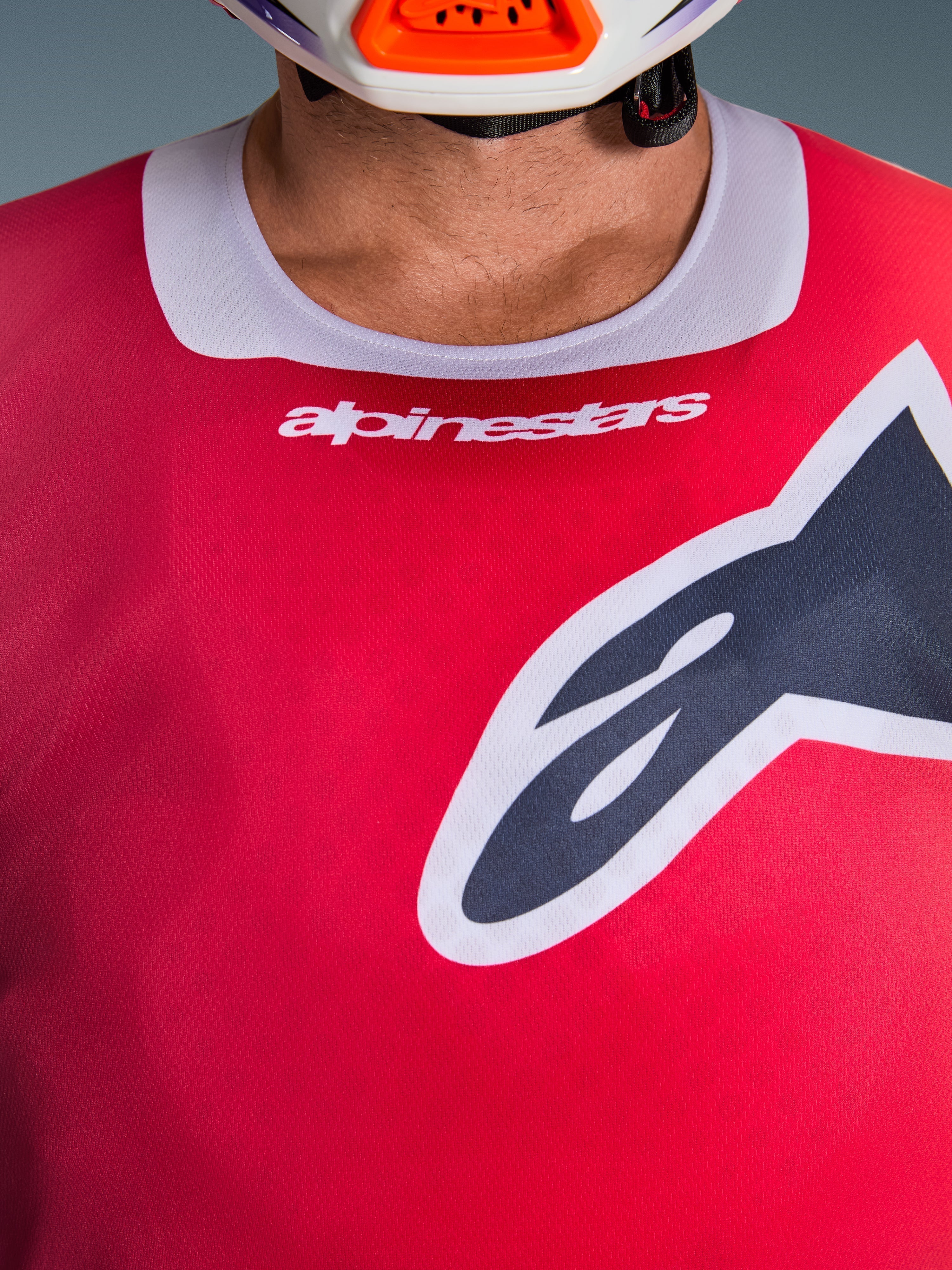 Close-up of the Alpinestars 2026 Racer Portl Jersey in Red, featuring a light gray stretch collar with white branding and a large black Astars logo on the chest, performance motocross racing gear