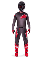 Motocross rider wearing complete racing gear, 2025 Supertech Lipan Jersey in Smoke Bright Red, matching grey pants with red logos, bright red boots, black helmet with goggles, and red and black gloves, professional motocross outfit.