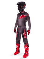 Motocross rider wearing complete racing gear, Smoke Bright Red 2025 Supertech Lipan Jersey, matching grey pants with red graphics, black helmet with red accents, bright red boots, and red and black gloves, coordinated professional outfit for off-road racing