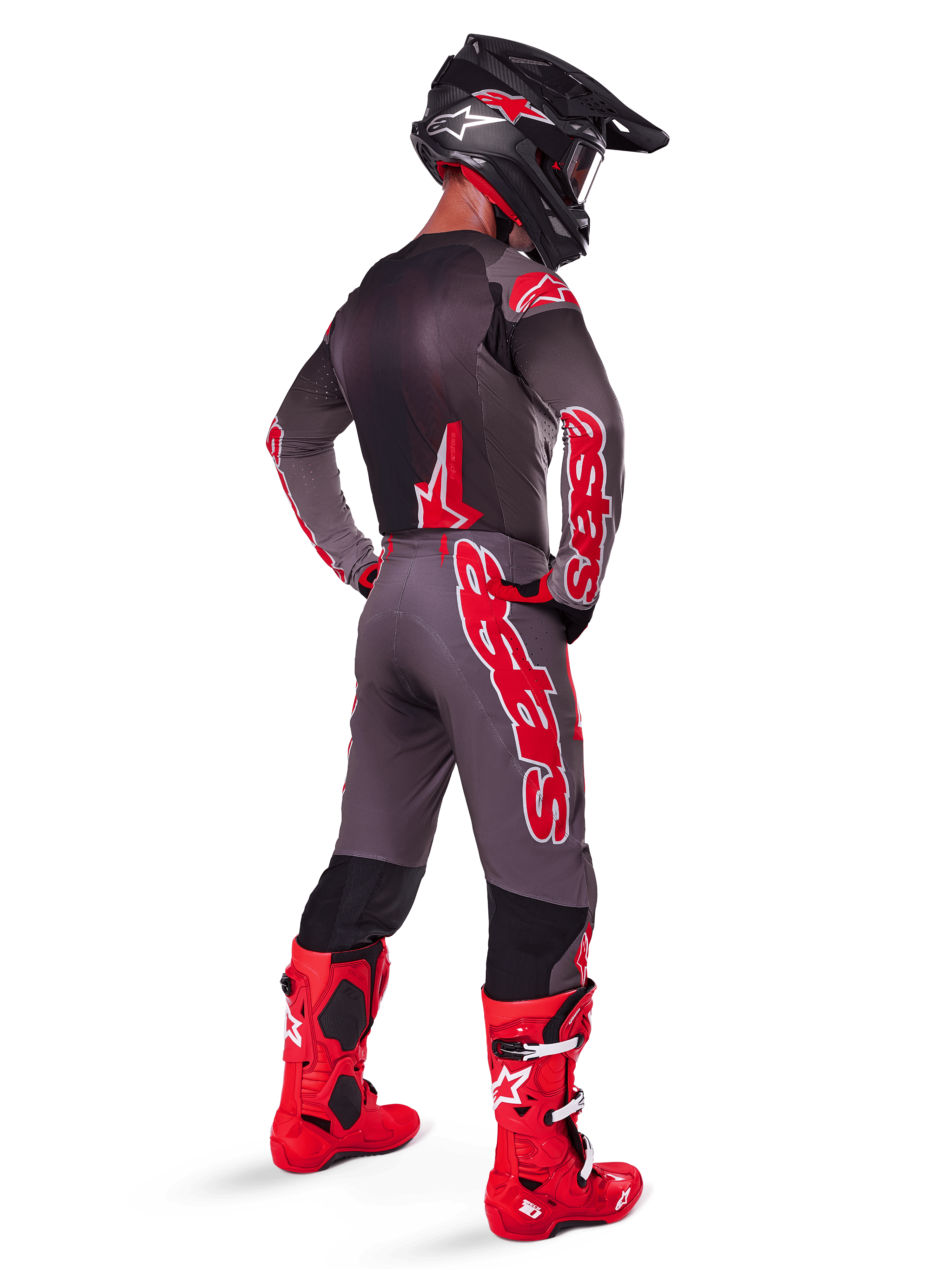 Motocross rider wearing 2025 Supertech Lipan Jersey, Smoke Bright Red, viewed from behind with matching grey and red pants, bright red boots, black helmet with red accents and red goggles, coordinated pro-level gear set for off-road racing