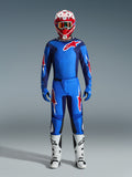 Motocross rider wearing the Alpinestars 2026 Fluid Grid Jersey in Blue and Red, matching blue pants with white and red star logos, red and white helmet with mirrored goggles, blue gloves, and white and black racing boots, complete off-road gear set.