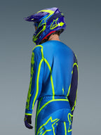 Alpinestars 2026 Fluid Apex Jersey, Blue Yellow Fluo, back view of rider wearing matching motocross pants and helmet, featuring fluorescent yellow geometric graphics and a relaxed athletic fit, coordinated off-road racing gear