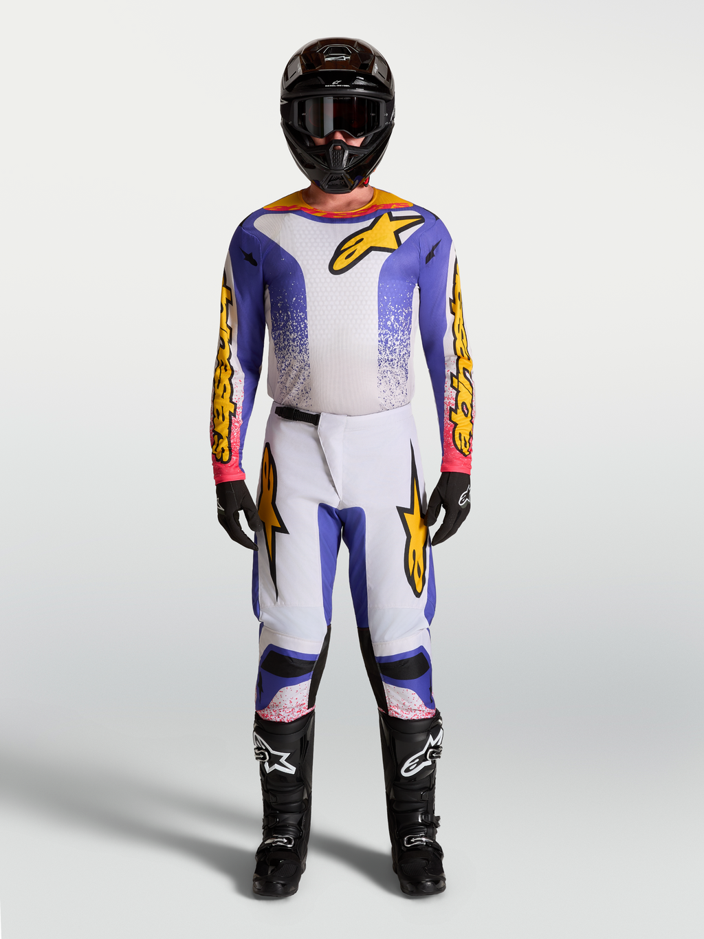 Alpinestars Fluid Drag motocross gear set in lilac, blue, and gold, featuring a matching jersey and pants.