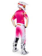 Motocross rider wearing complete racing gear, Pink Fluo and White Limited Edition Supertech AFD MIG Jersey, matching white and pink pants with orange branding, white helmet with pink accents and orange goggles, white and black motocross boots, coordinated outfit for off-road racing