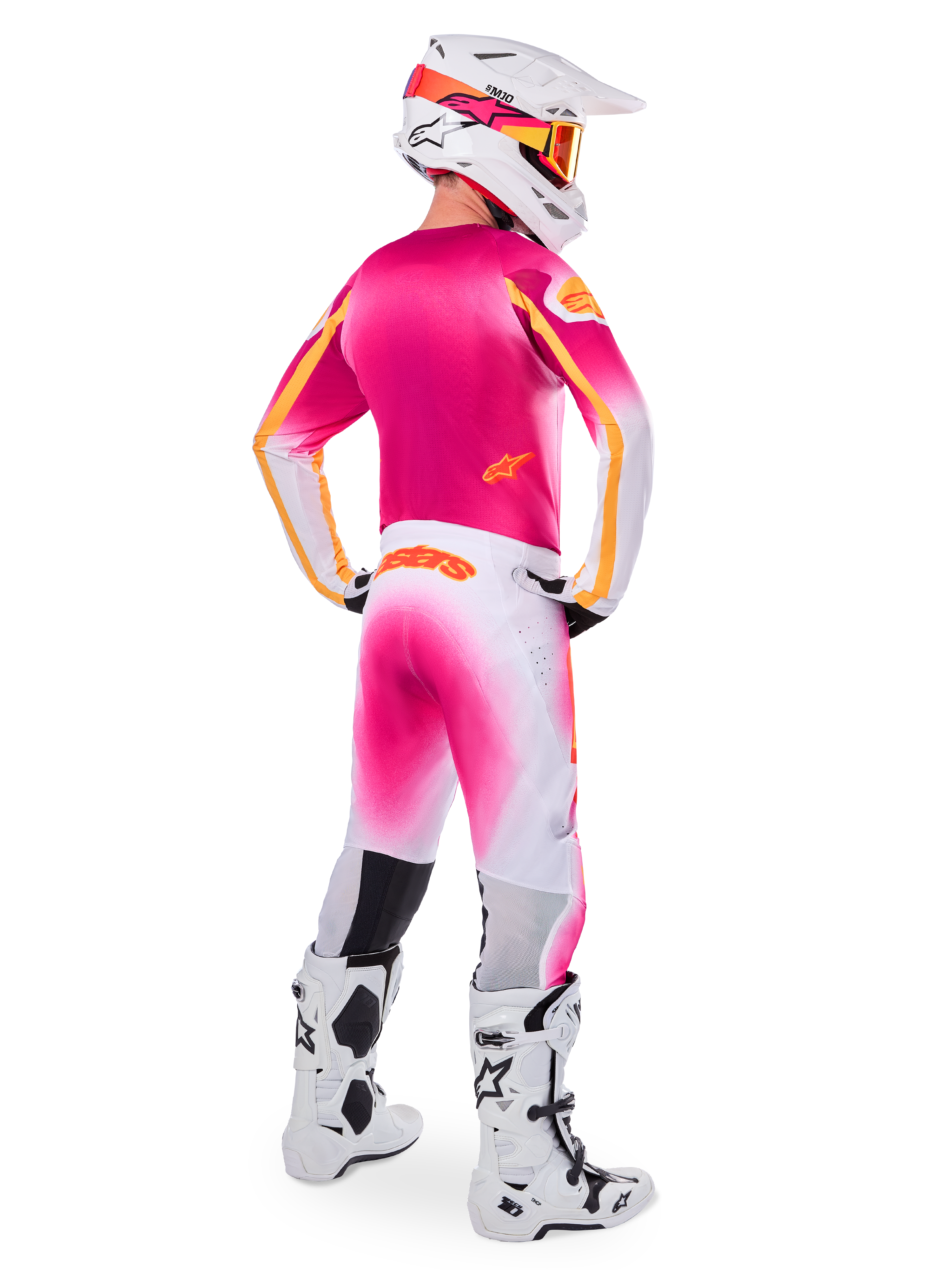 Motocross rider wearing complete racing gear, Pink Fluo and White Limited Edition Supertech AFD MIG Jersey, matching white and pink pants with orange branding, white helmet with pink accents and orange goggles, white and black motocross boots, coordinated outfit for off-road racing