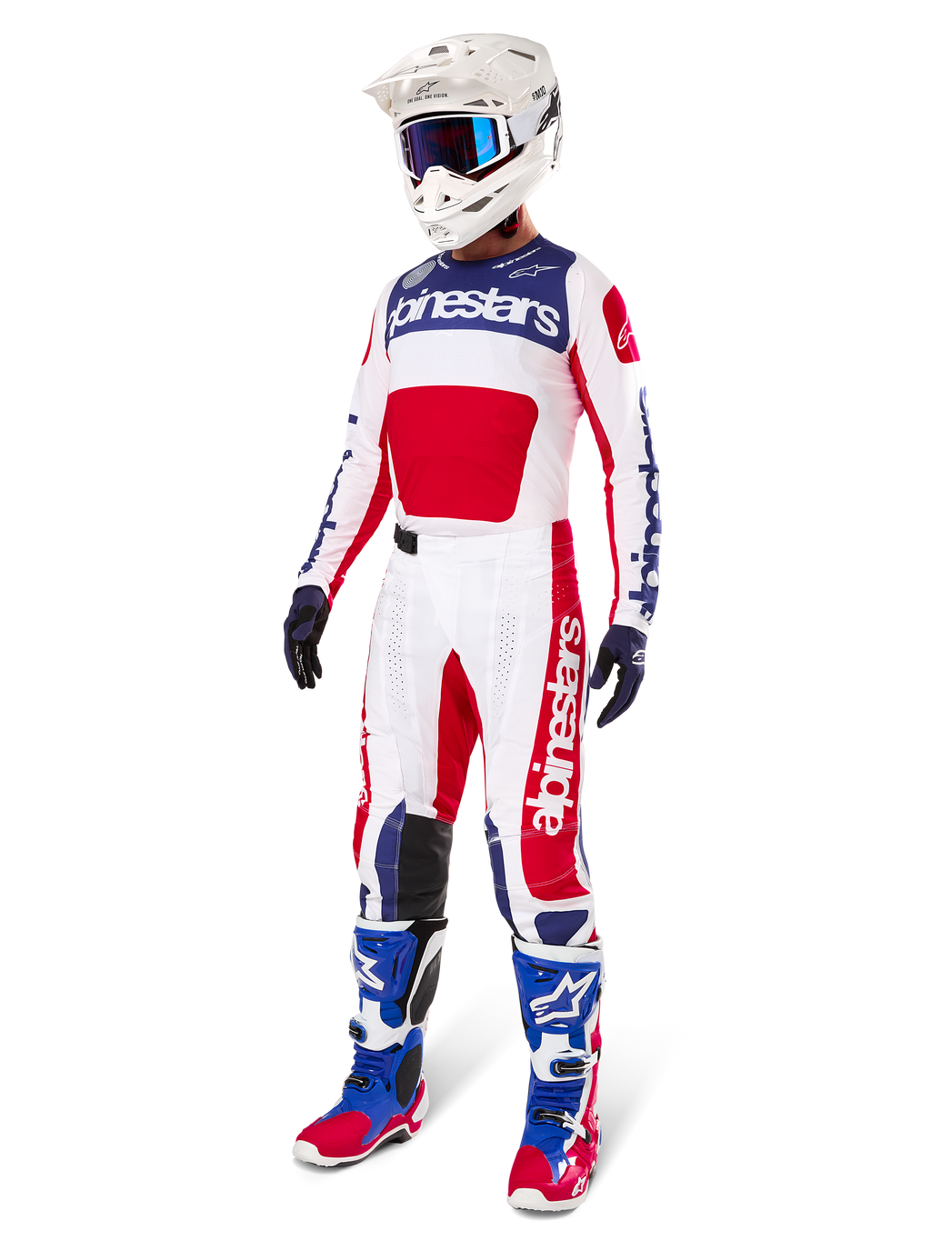 Motocross rider wearing complete racing gear, featuring the Alpinestars Limited Edition Techstar Fortitude Jersey in Bright Red, White, and Blue. Matching motocross pants, white helmet with blue goggles, and blue and red boots, providing a coordinated look for off-road competition.