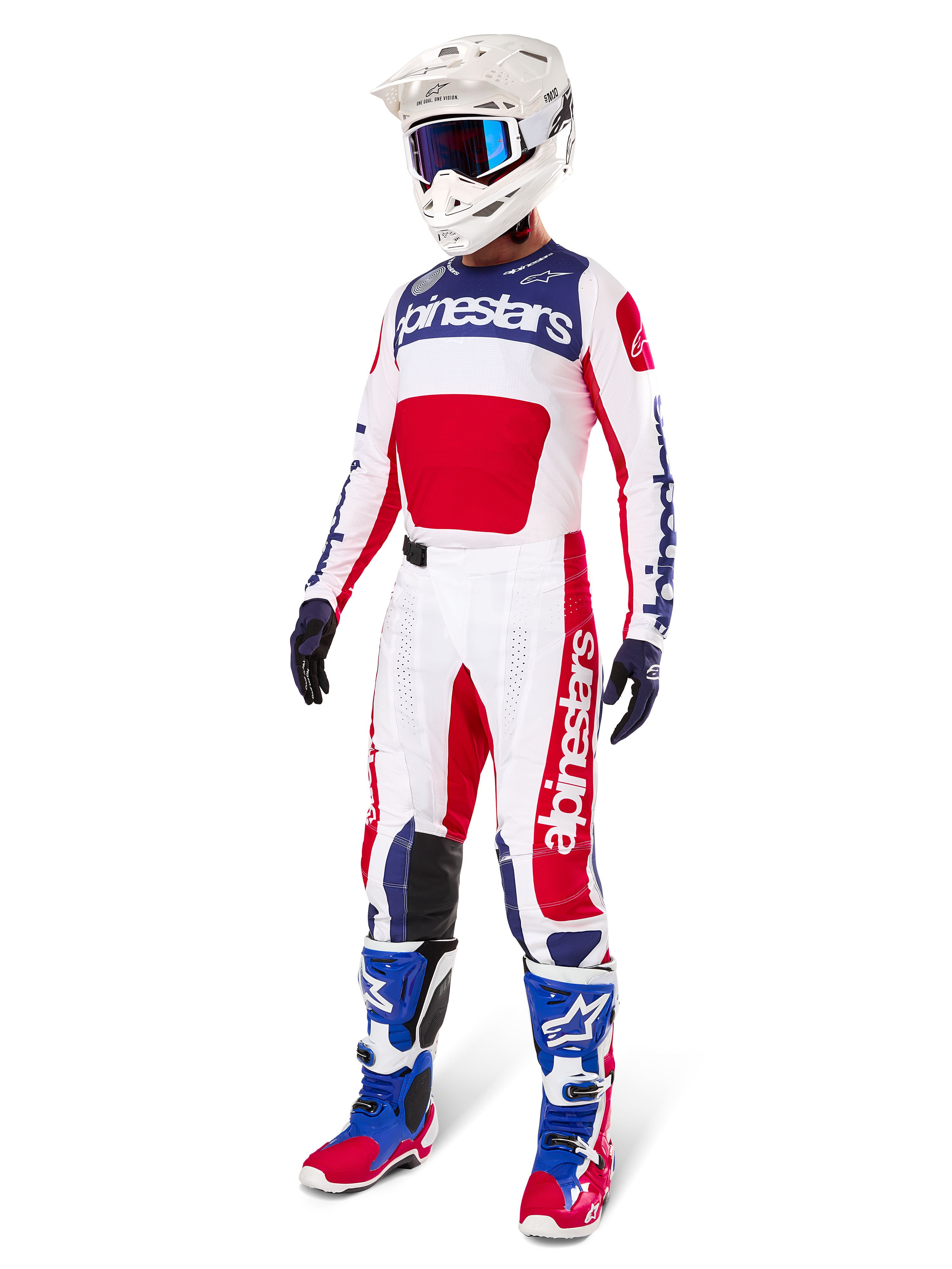 Motocross rider wearing complete racing gear, featuring the Alpinestars Limited Edition Techstar Fortitude Jersey in Bright Red, White, and Blue. Matching motocross pants, white helmet with blue goggles, and blue and red boots, providing a coordinated look for off-road competition.