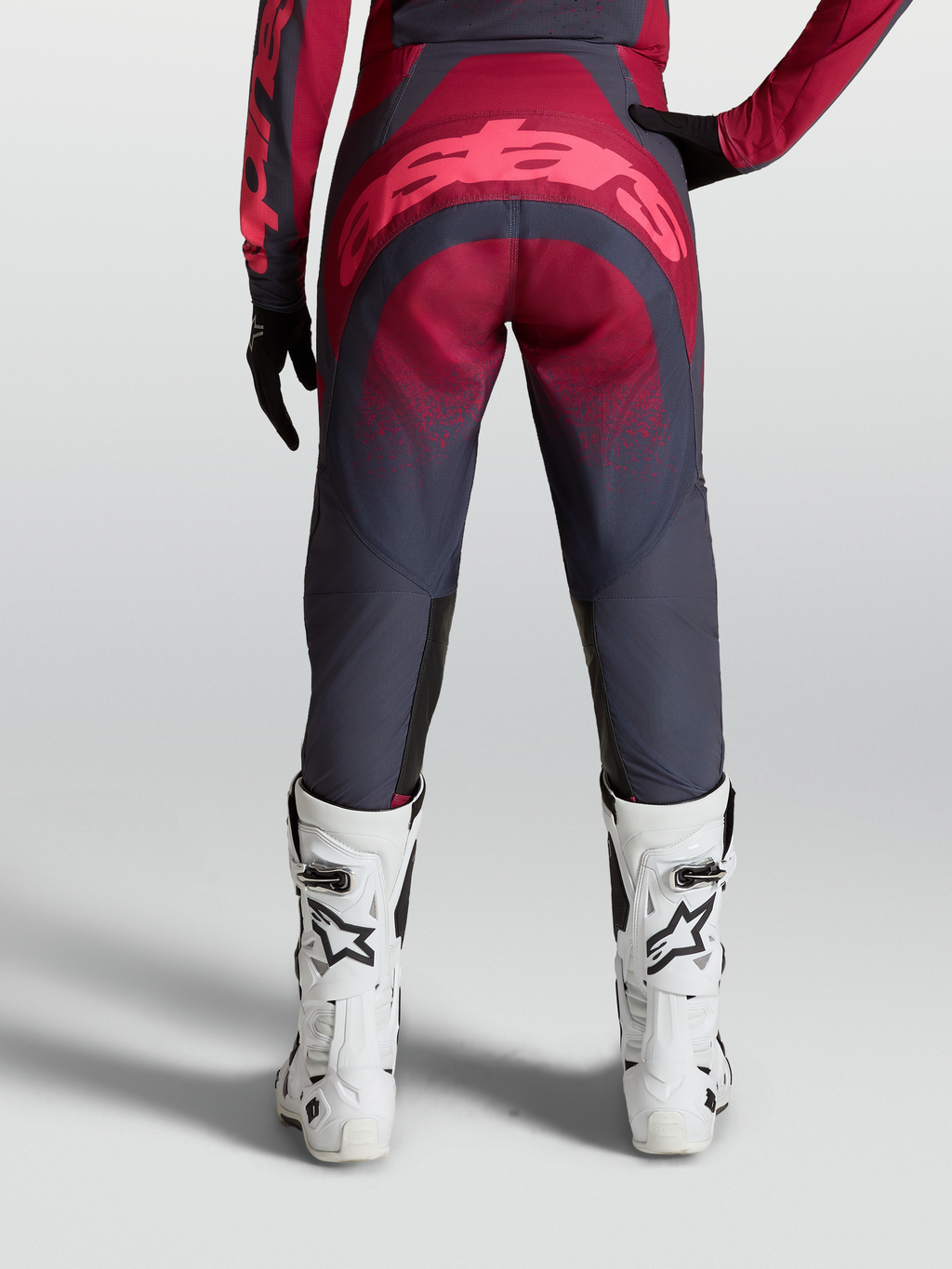 Alpinestars Stella Techstar Swan Pants, women's performance motocross gear, crimson and dark gray, durable 600D polyfabric and stretch ripstop construction, reinforced seat area, on-model rear view with white racing boots.