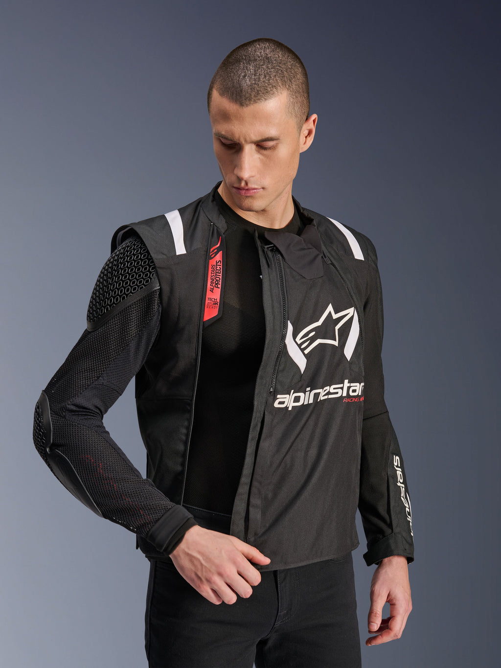 Alpinestars T-Stunt Air Jacket, Black and White motorcycle jacket, worn by male model, showcasing modular mesh construction and exposed internal armor on shoulder and elbow, Alpinestars branding on chest, Tech-Air Ready feature, sports-cut for road riding