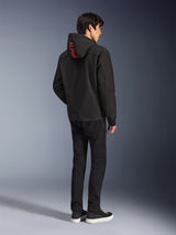 Alpinestars Radium Tech Hoodie, Black with red Alpinestars branding on the hood, back view on a male model, worn with black pants and sneakers, technical urban riding gear