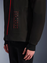 Alpinestars Radium Tech Hoodie, Urban Motorcycle Jacket, Black and Bright Red, close-up of front graphic with vertical red text "ALPINESTARS ONE GOAL ONE VISION", red zipper, and ribbed cuff with thumbhole.