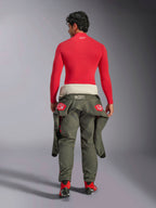 Alpinestars ZX Evo V3 Top - Long Sleeve, Red Auto Base Layer, back view of a male model wearing the fire-resistant top with olive green racing pants tied at the waist and red racing boots, professional motorsport gear.