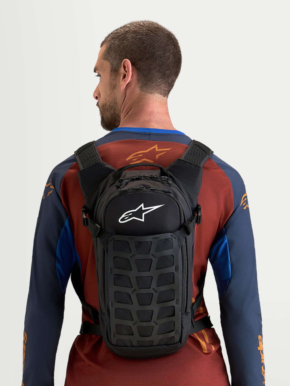 Alpinestars AT-9 Backpack, motocross backpack worn by a model, black textile construction with white Alpinestars logo, compact design for track and daily carry
