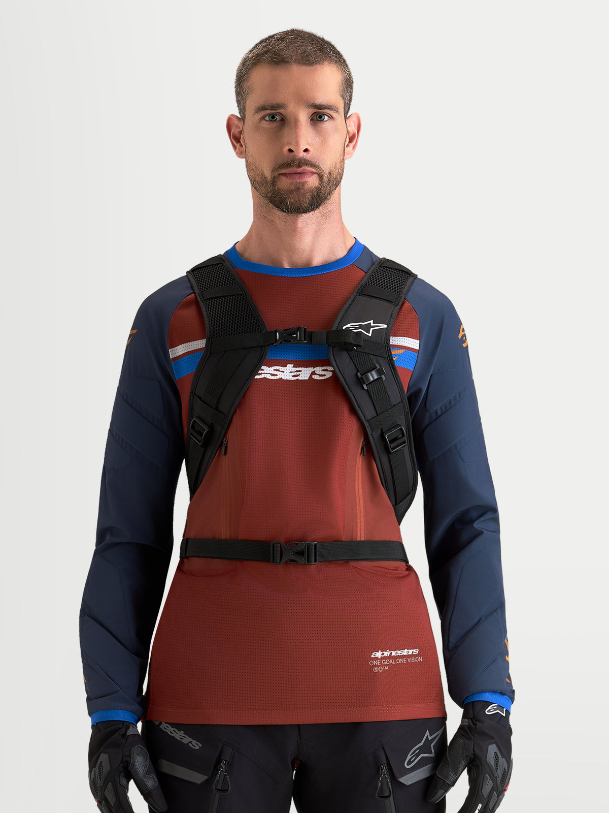 Alpinestars AT-9 Backpack, motocross backpack in black and deep gray, front view worn by a male model with padded shoulder harness and chest buckle system