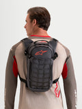 Alpinestars AT-9 Back Pack, motocross and everyday utility backpack worn by a model, walnut and deep gray textile construction, featuring organized storage compartments and a distinctive red Astar logo