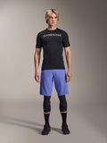 Alpinestars A-Aria Lite Short in Baja Blue, Men's MTB Shorts, worn with a black short-sleeve jersey and protective knee guards, featuring laser perforations for ventilation, mountain bike performance gear