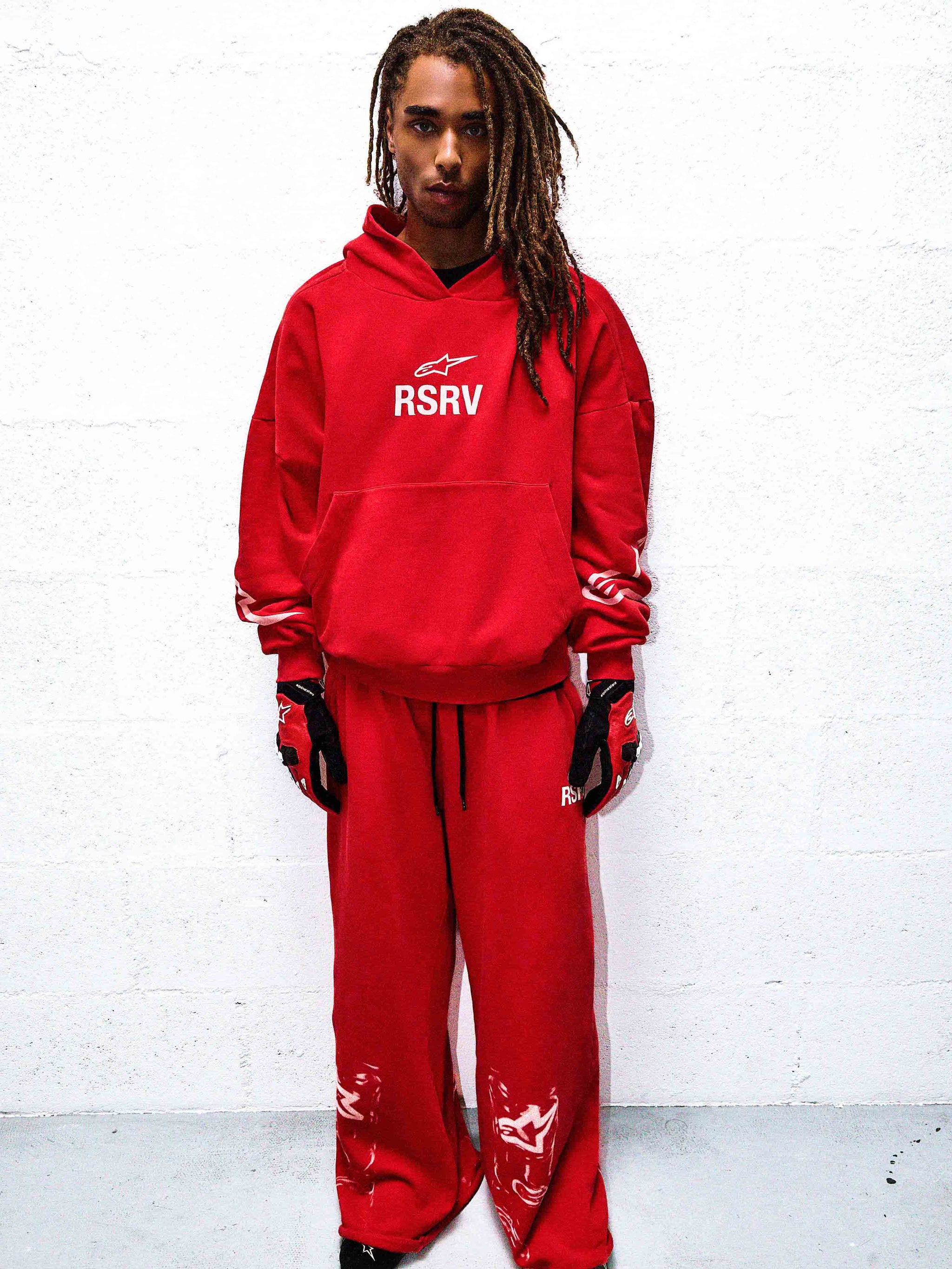 Alpinestars RSRV 2Stars Hoodie, Red, lifestyle streetwear, person wearing bright red hoodie with white RSRV logo, matching red sweatpants, premium casual motorsport-inspired apparel