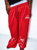 Alpinestars RSRV Tech 10 Sweatpants, Red streetwear joggers with white RSRV logo on thigh, glossy white abstract pattern at ankles, black drawstring waist, premium lifestyle collection