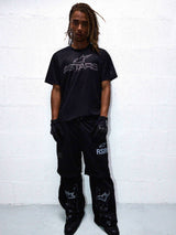RSRV Fluid Reworked SS Jersey, black t-shirt with ASTARS graphic, worn with RSR pants, black gloves and boots, urban streetwear styling, monochromatic black outfit, motorsport-inspired fashion