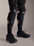 Alpinestars A-Impact Plasma Pro Knee Shin Protectors, Black and White, featuring the white Alpinestars logo and triple strap closure system, worn with black socks and black athletic shoes, durable off-road cycling protection