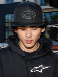 Alpinestars Contender Trucker Hat, black lifestyle cap with poly mesh back, structured crown featuring an embroidered Astars logo patch, worn by a man with a black Alpinestars hoodie, casual motorsport-inspired streetwear.