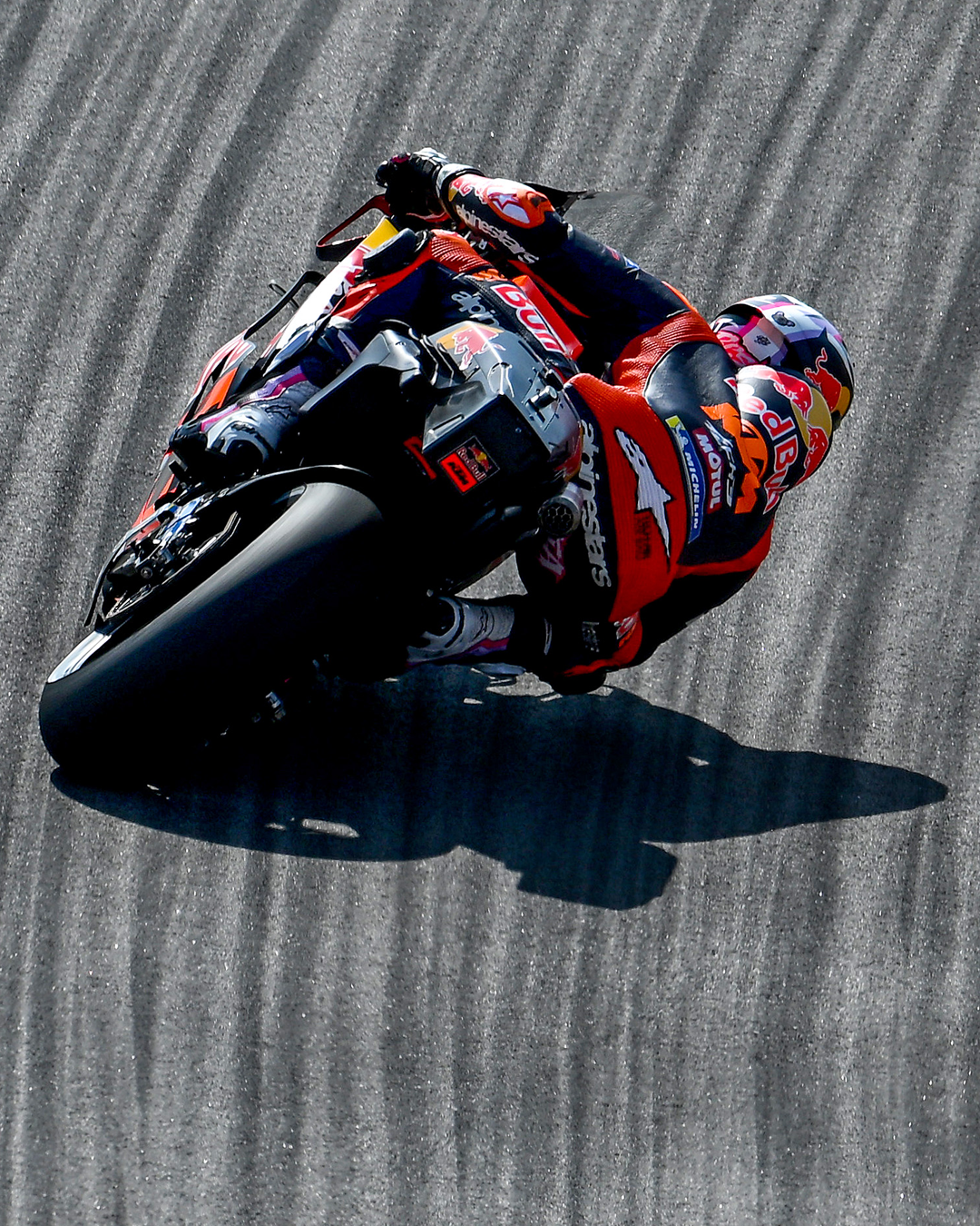 Enea Bastianini in red and blue Alpinestars racing suit leaning into a turn on a racetrack