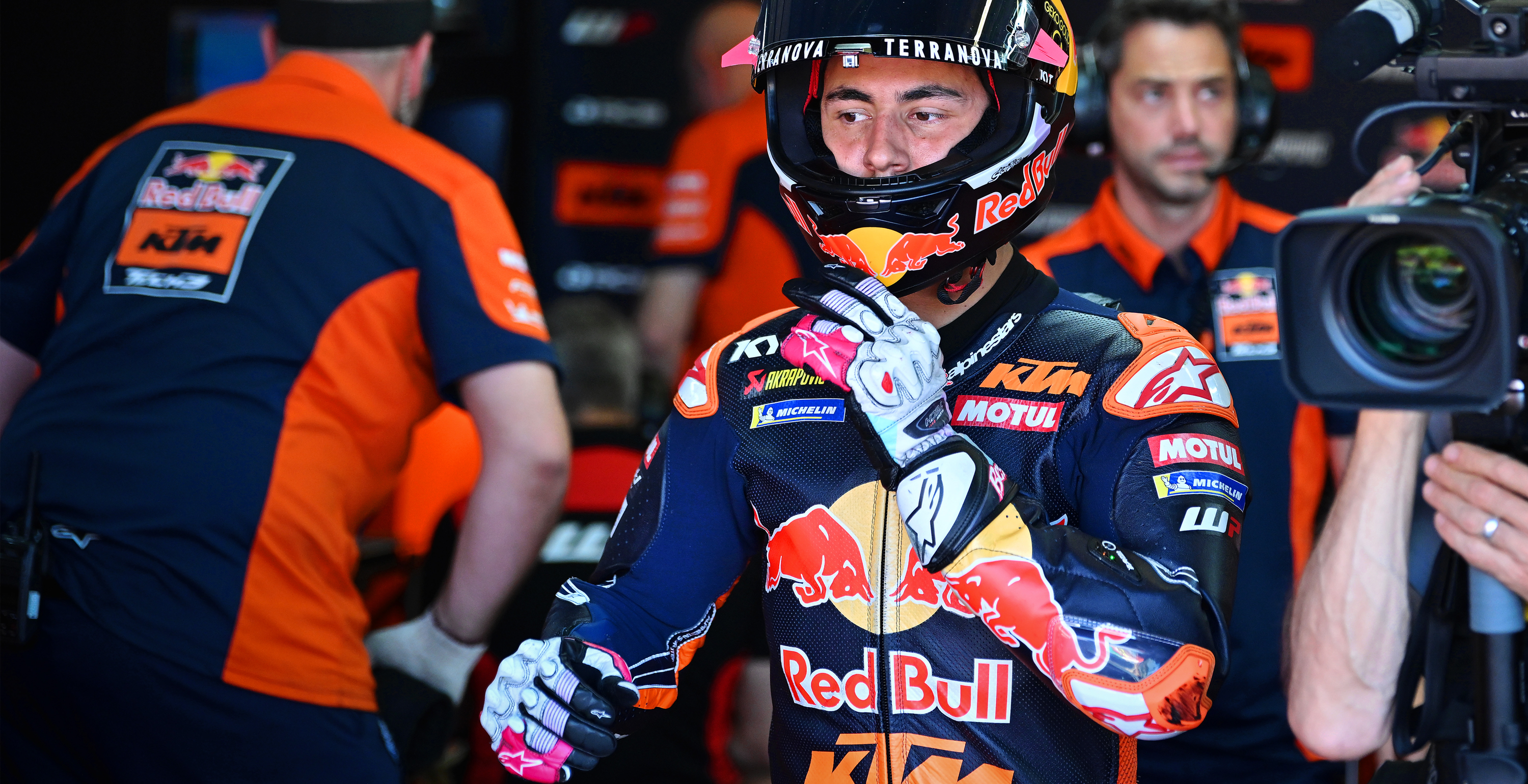 Bastianini in full gear with Red Bull and KTM branding in a pit lane setting.