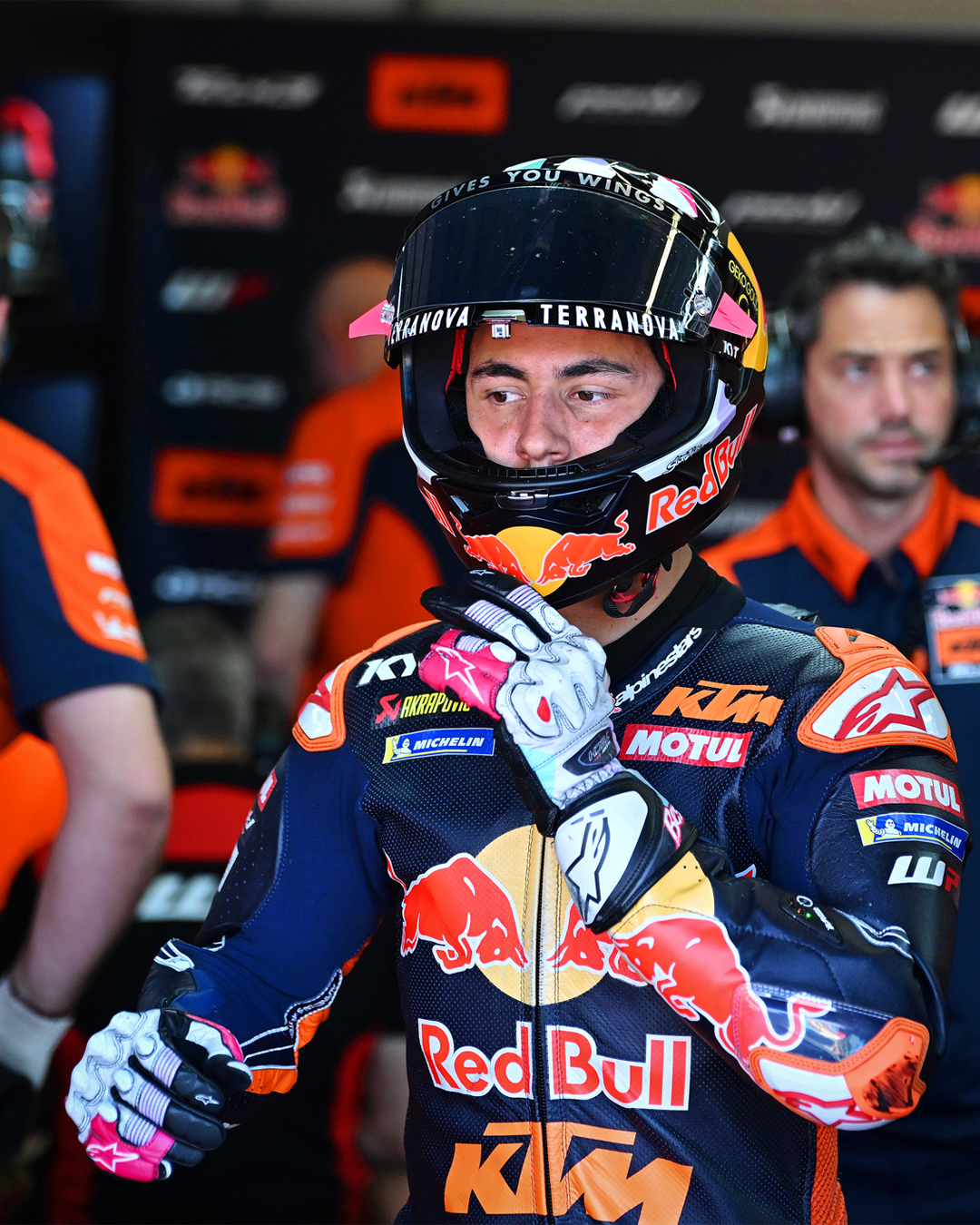 Bastianini in full gear with Red Bull and KTM branding in a pit lane setting.
