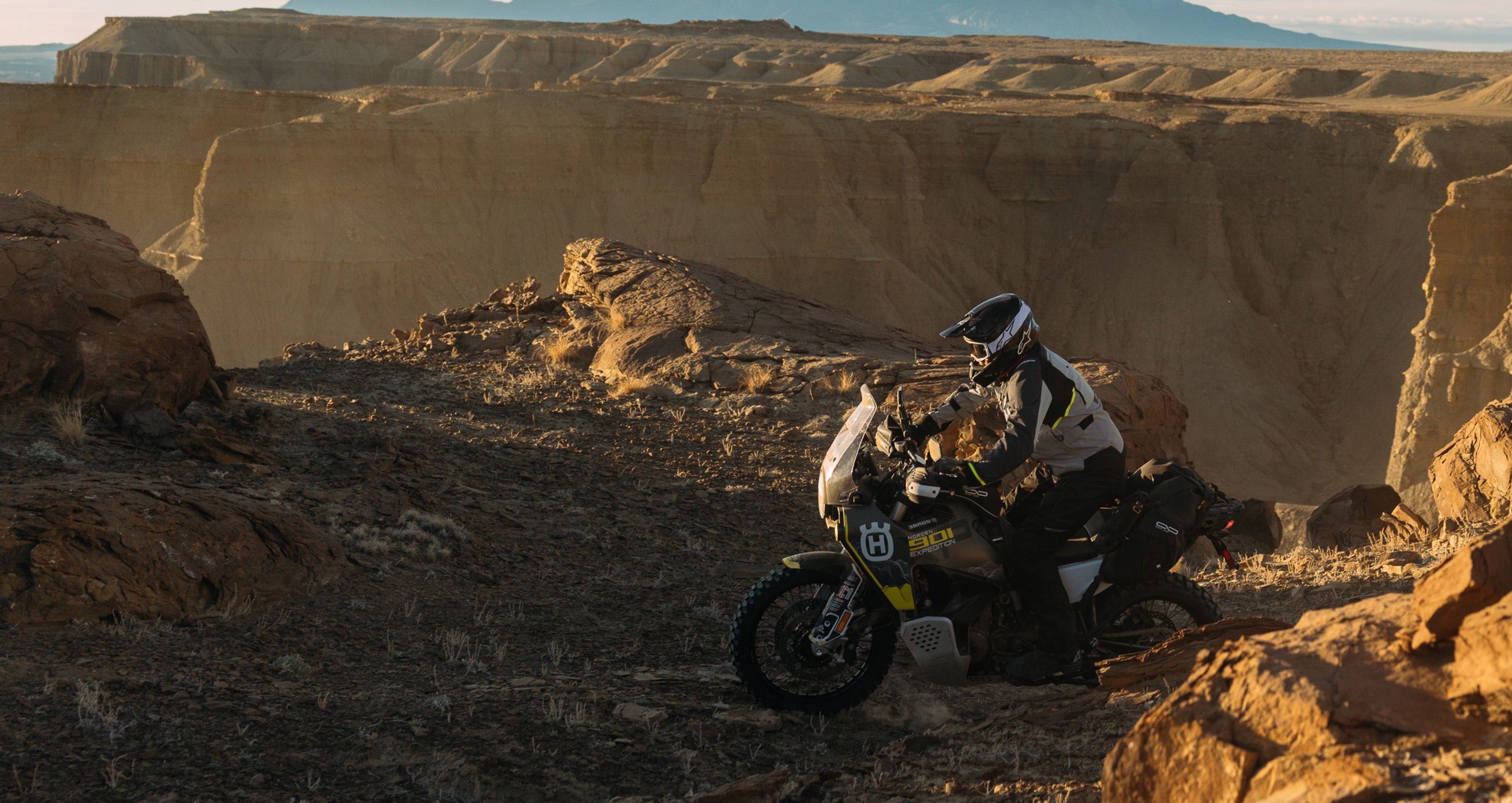 Alpinestars Cusco Drystar® Jacket and Pants, gray and black adventure motorcycle gear, desert riding in a canyon.