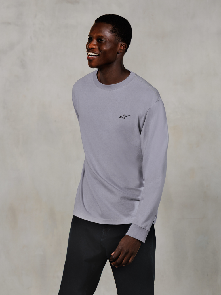 Alpinestars Essentials Ageless LS Tee, Long Sleeve T-Shirt, Silver, small black logo on the chest, worn by a smiling model with dark pants, relaxed contemporary fit, casual motorsport lifestyle apparel