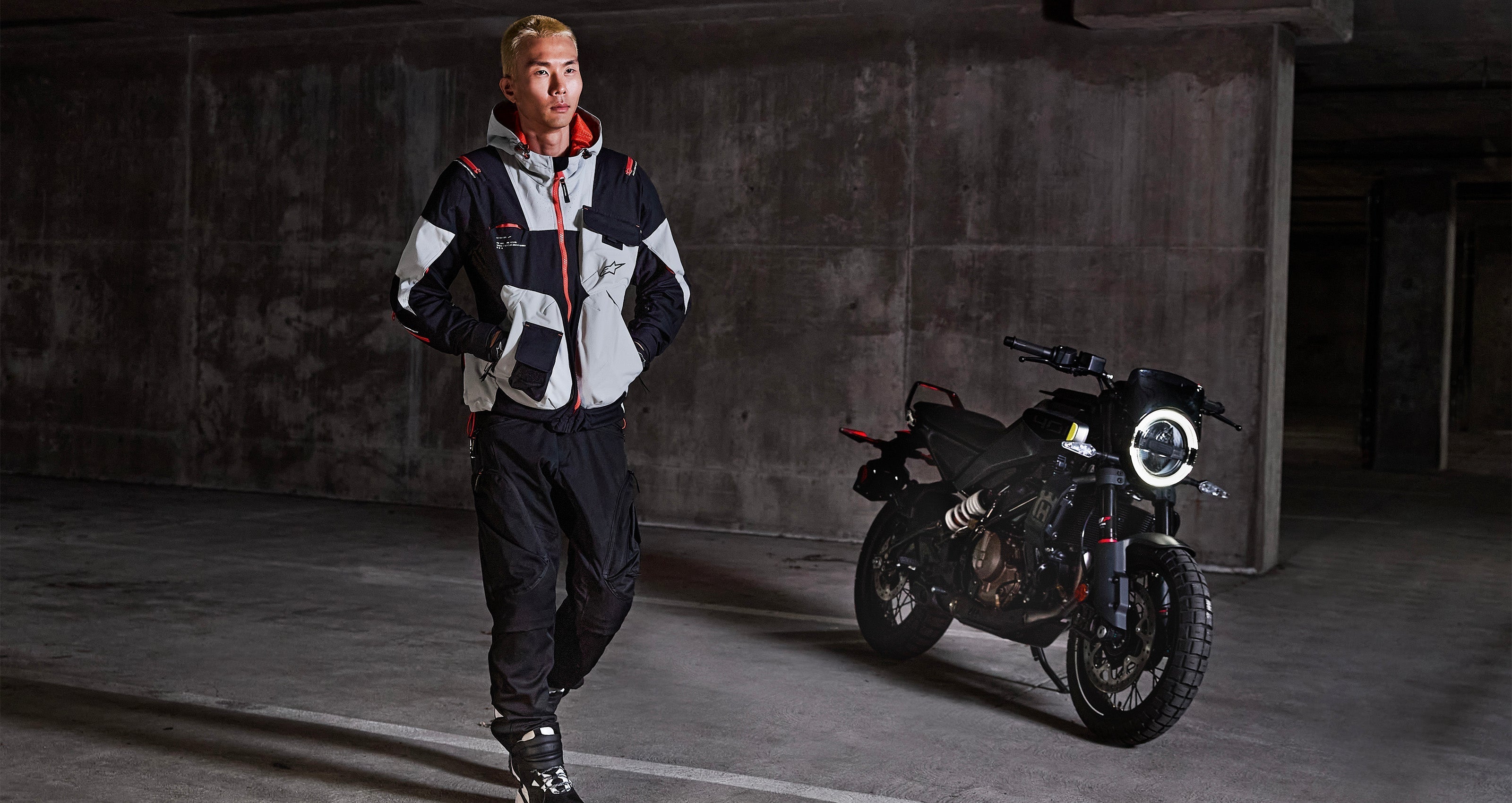 Alpinestars Mogress Air Jacket in Black and Almond with Hot Orange, urban textile motorcycle jacket worn in a parking garage.
