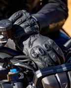 Alpinestars SP X 7 black perforated leather motorcycle gloves with TPU knuckle protection on motorcycle handlebars.