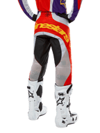 Alpinestars 2024 Techstar Ocuri Pants, Motocross Pants, Hot Orange Purple and Black, back view from the waist down, bold yellow branding across the seat, black and grey technical panels, paired with white motocross boots.