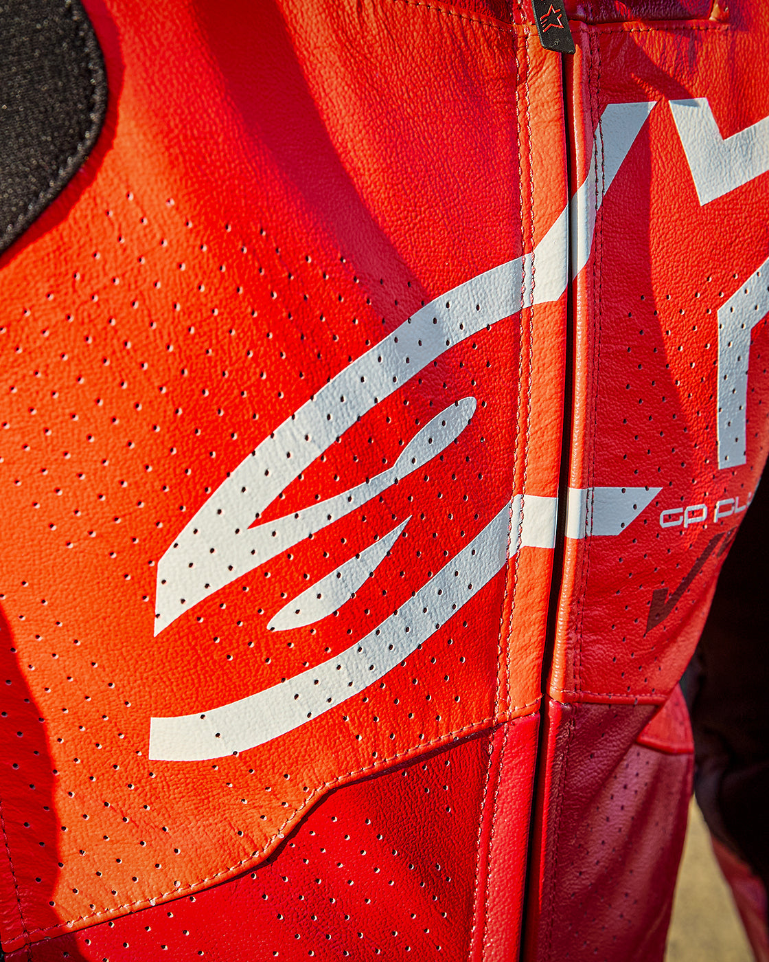 Alpinestars GP Plus V4 Sprint Leather Suit in Red Fluo, close-up of perforated racing leather and white logo.