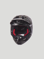 Alpinestars Supertech M10 Solid Helmet  Black Glossy Carbon Motocross Helmet with red interior padding. High-performance off-road racing protection featuring a 3K carbon shell, MIPS technology, and 28-port ventilation system for maximum airflow.